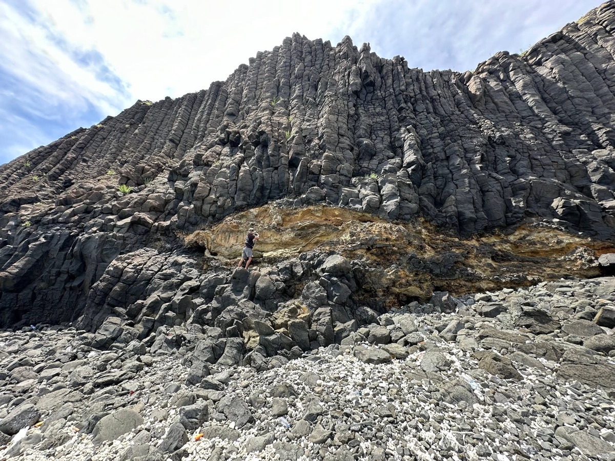 Geologist examining a dramatic columnar rock outcrop